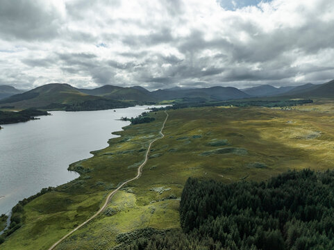 Aerial view of tranquil Loch Tulla surrounded by majestic mountains and lush forest, Bridge of Orchy, Scotland.