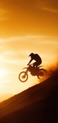 Obraz premium A silhouette of a motocross rider soaring over a sand dune against a vibrant sunset, embodying freedom and adventure.