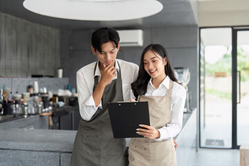 Young Barista Couple Reviewing Menu in Modern Coffee Shop Interior with Natural Light