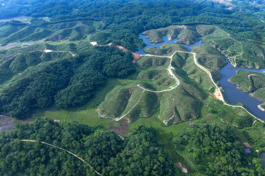 Aerial view of the serene Ramgarh Tea Garden surrounded by lush hills and a winding road, Khagrachari District, Bangladesh.