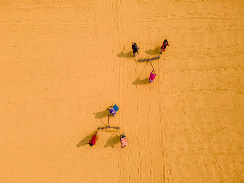 Aerial view of sun dried paddy fields and a rice mill with workers, Brahmanbaria, Bangladesh.