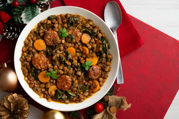 Lentil stew with chorizo, spinach and carrot. Top view table with Christmas decorations.