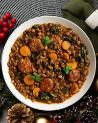 Lentil stew with chorizo, spinach and carrot. Top view table with Christmas decorations.