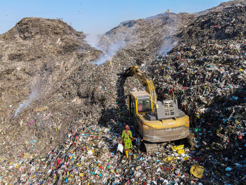 Chittagong, Bangladesh - 09 March 2024: Aerial view of a dirty garbage depot with bulldozers and workers, Halishahar, Chittagong, Bangladesh.