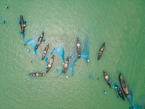 Aerial view of fishing boats with blue nets on the serene Sundarban River surrounded by mangroves, Khulna, Bangladesh.