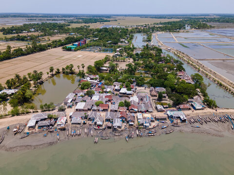 Aerial view of a peaceful fishing village with boats docked along the Sundarban river in a coastal area surrounded by mangrove forest, Khulna, Bangladesh.
