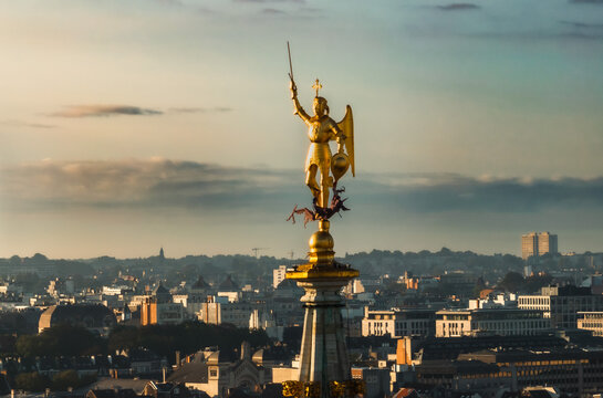 Golden statue over a city holding a sword