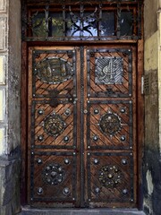 Ornate wooden door with intricate carvings and metal accents, showcasing traditional craftsmanship in a historical building entrance.