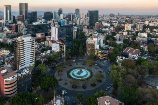 Aerial view of fuente de cibeles surrounded by modern buildings and lush greenery at sunset, Cuauhtemoc, Mexico City, Mexico.