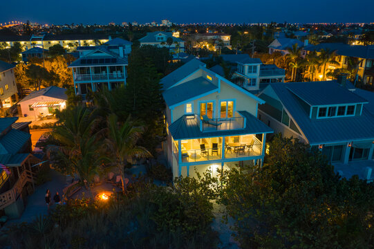Saint Pete Beach, United States - 23 March 2019: Aerial view of a beautiful residential beach house with lit windows and palm trees, Saint Pete Beach, United States.