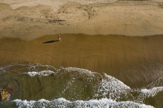 Aerial view of serene Playa Troncones beach with a person and their shadow on the sandy shore, Guerrero, Mexico.
