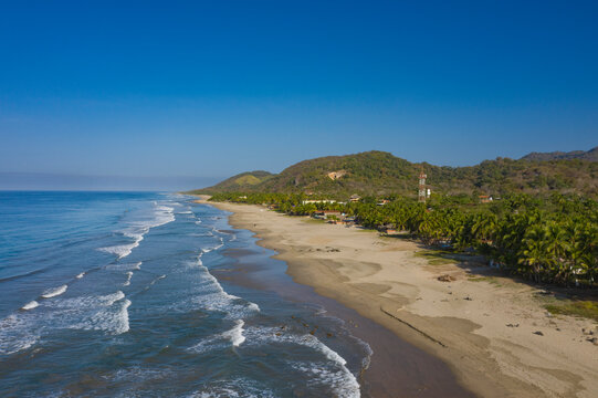 Aerial view of beautiful Playa Troncones with sandy beach and palm trees beside the tranquil ocean, Troncones, Mexico.