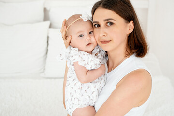 mom with a baby, an international family, a Caucasian mom with an Asian baby in her arms in the bedroom gently hugs him holding him in her arms, a place for text