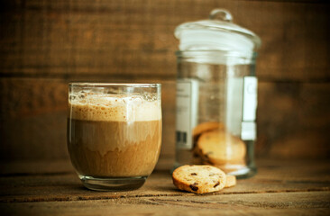 A coffee with milk and cookies on a wooden background