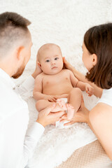 mom, dad with a baby, an international family, a Caucasian mom with an Asian husband and a baby in her arms in the bedroom gently hugs the baby holding in her arms, a place for text