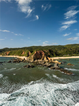 Aerial view of beautiful Adan Beach with tranquil waves and rocky coastline, Kunigami District, Japan.