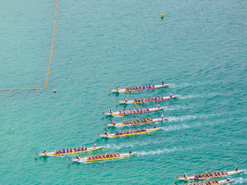 Aerial view of dragon boat races in vibrant blue water with people paddling, Stanley, Hong Kong.