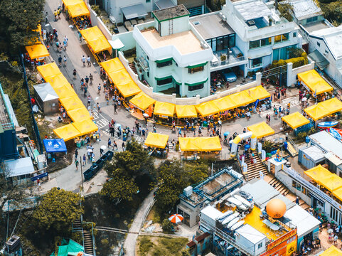 Aerial view of vibrant dragon's boat races with bustling market stalls and yellow tents, Stanley, Hong Kong.
