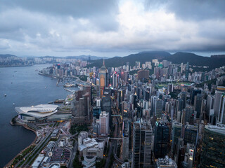 Aerial view of breathtaking skyline with modern skyscrapers and harbor surrounded by mountains at sunset, Hong Kong Central, Hong Kong.