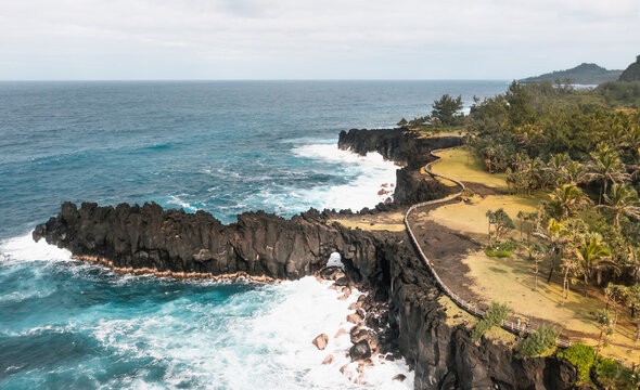 Aerial view of rough and wild cliffs with stormy waves and mist, Puits des Francais, Saint-Philippe, Reunion.