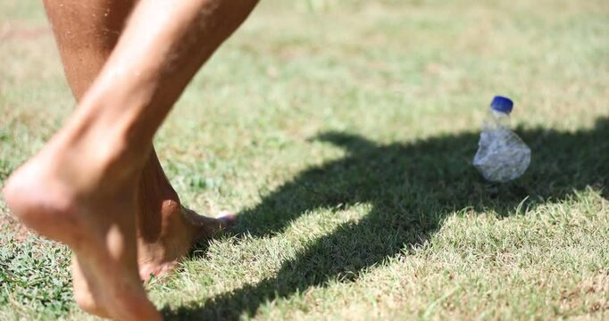 Unrecognizable man throws plastic bottle into grass. Problem of plastic in ecology plastic pollution of nature