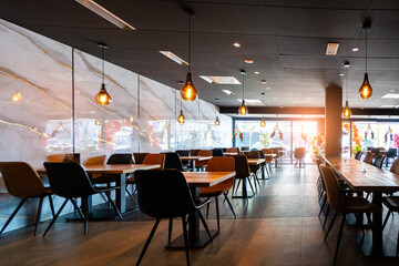 Cozy and modern coffee shop interior with wooden furniture, warm lighting, and large windows overlooking the street, creating an inviting atmosphere