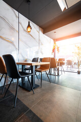 Cozy and modern coffee shop interior with wooden furniture, warm lighting, and large windows overlooking the street, creating an inviting atmosphere