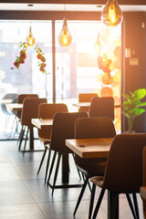 Cozy and modern coffee shop interior with wooden furniture, warm lighting, and large windows overlooking the street, creating an inviting atmosphere