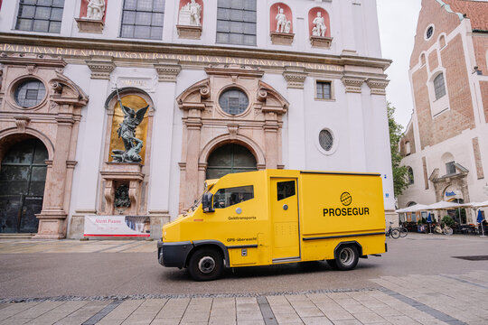 Munich, Germany - September 13, 2024 - A yellow Prosegur armored truck parked outside a historic building with statues and an ornate facade in Munich, Germany.