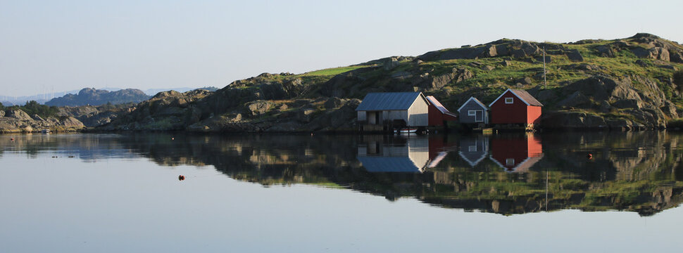 Boat sheds reflecting in the sea, Rogaland, Norway.