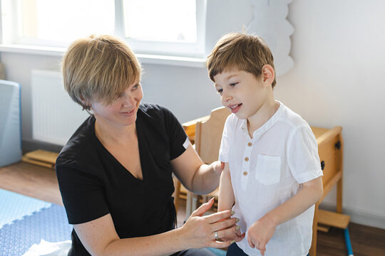 Little boy with cerebral palsy receives support from a therapist during a rehabilitation session in rehab clinic