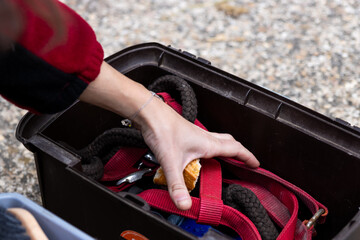 Hand reaching into a horse tack box with reins and grooming tools