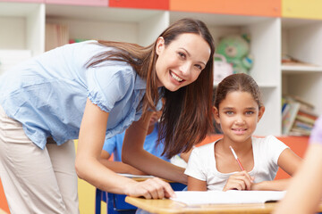 Education, portrait and teacher with student in classroom for learning, knowledge and studying. Happy, advice and female educator talk to girl child for assistance in lesson at school for scholarship