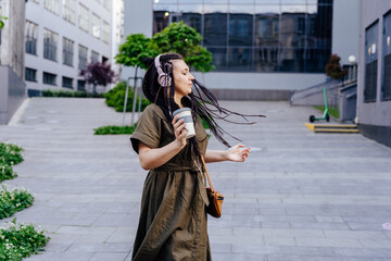 People, middle age, fun and active lifestyle concept. Happy mid adult woman enjoying listening to music through headphones outdoor.