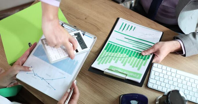 Businessman with financial report considers figures on calculator and discusses sales growth with colleague. Collaboration and business budget planning