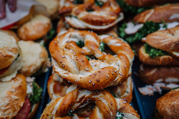 Munich, Germany - September 13, 2024 - Close-up of freshly baked Bavarian pretzels topped with salt, served with cream cheese and herbs, displayed with other traditional bread rolls.