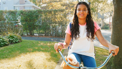 Obraz premium Portrait Of Girl Wearing Backpack Riding Her Bike Along Suburban Street On Her Way To School