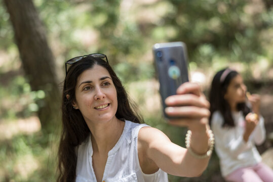 woman taking self portrait with daughter in background