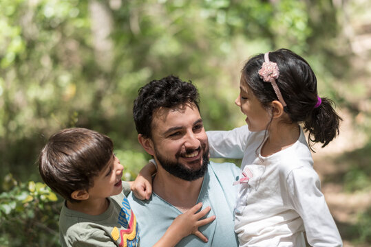 Father with son and daughter playing in pine forest