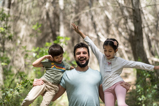 Father with son and daughter playing in pine forest