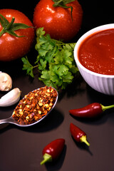 ingredients for making ketchup. ketchup in a white bowl on the table with tomatoes and parsley.