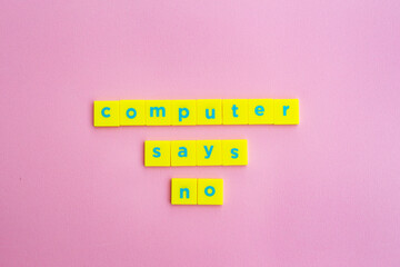 'Computer says no' statement in blue letters on yellow plastic squares against pink paper