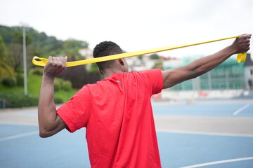 Rear view of an african sportsman stretching with elastic band