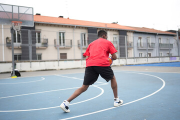 African American man playing basketball outdoor at urban court