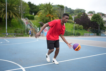 Obraz premium African man playing on the basketball court dribbling a ball