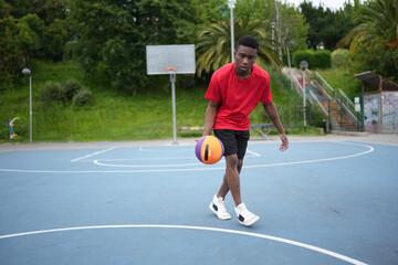 Obraz premium Dribbling drills by african man on outdoor basketball court