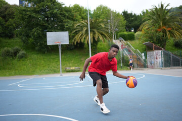 African sportive young man playing basketball outdoors