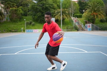 Obraz premium African young man playing basketball alone in a park