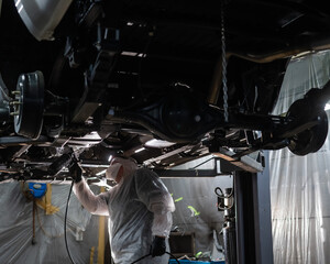 The master sprays an anti-corrosion compound on the bottom of the car. 