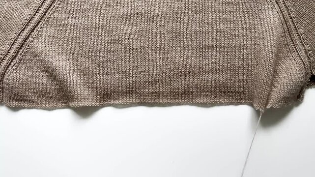 Unraveling a beige hand-knitted wool sweater. A failed knitting project.
